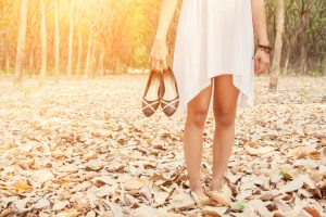 Young woman carrying shoes when she tired to walk in forest